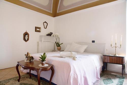a bedroom with a white bed and a table at Dimora Ettore - Lago Maggiore in Casalzuigno