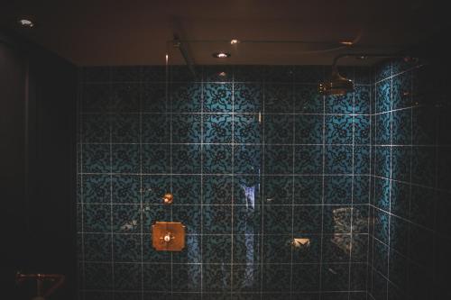 a bathroom with a blue tiled wall at Le Petit Chateau & William de Percy in Otterburn