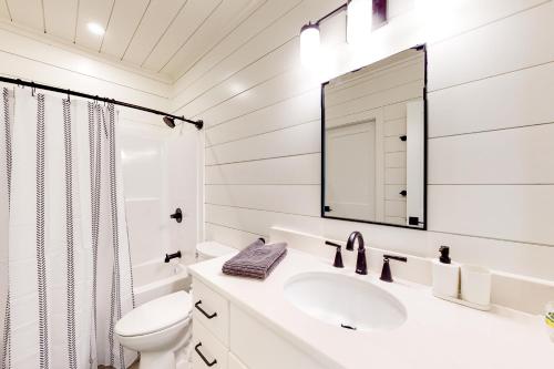 Baño blanco con lavabo y espejo en Fjallstuga, en Rangeley
