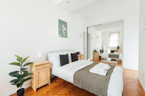 a white bedroom with a large bed and a mirror at Unique 2 Bedroom Flat on Stoke Newington High Street in London