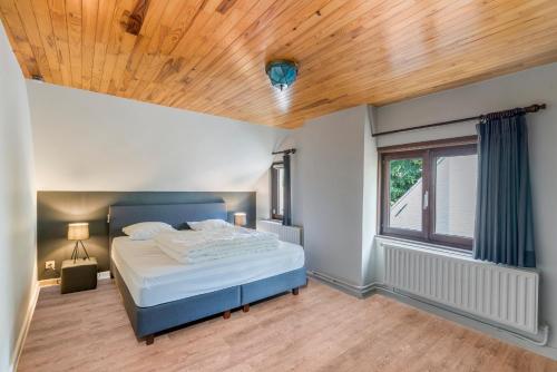 sypialnia z łóżkiem i drewnianym sufitem w obiekcie Fantastische vakantiewoning aan het bos w mieście Wingene