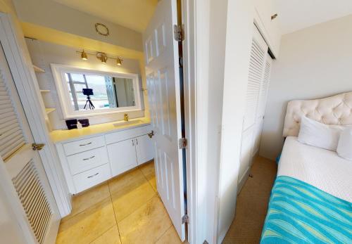 a bedroom with a bed and a sink and a mirror at One-Bedroom Apartment in Honolulu