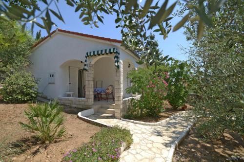 a small white house with a garden and flowers at Holiday Park Mandrice in Mandre