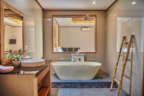baño con bañera grande y espejo grande en Sawitri Anandhita Luxury Villas en Ubud