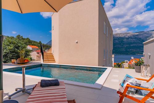 a swimming pool sitting next to a house with an umbrella at Luxury Nest Maretta & Oliva in Korčula