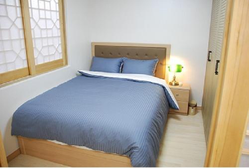 a bedroom with a blue bed and a window at Beverly Hills Suite Residence in Geoje