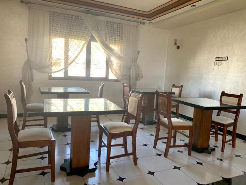 a dining room with tables and chairs and a window at Maison d'hôtes familiale "Dar Aboulanwar" in El Jadida