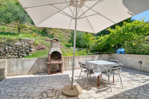 a table and chairs with an umbrella and an oven at Villa Old Olive in Budva