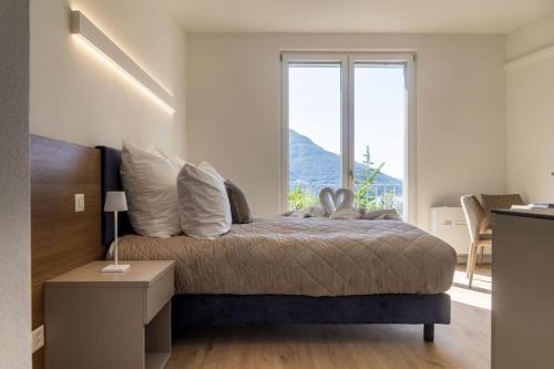 1 dormitorio con cama y ventana grande en Lake Blues, en Brissago