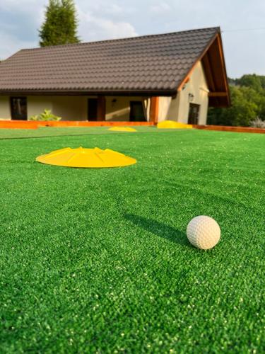a golf ball sitting on the grass next to a yellow frisbee at Przytulny Domek z Banią - Brzozowy Zagajnik MK in Brzozowa