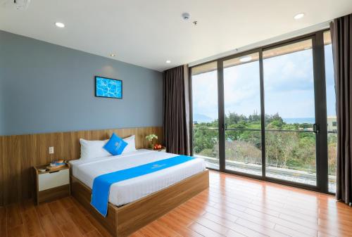 a bedroom with a large bed and large windows at Havana Con Dao Hotel in Con Dao