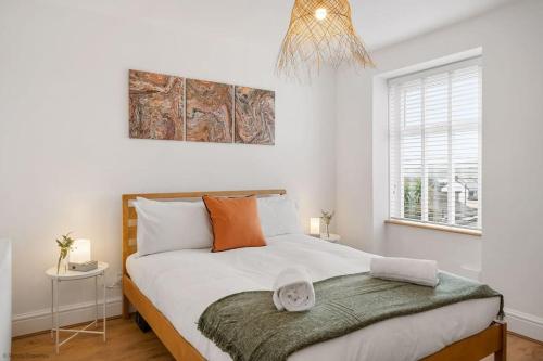 um quarto com uma cama com lençóis brancos e almofadas laranja em Stylish & Modern Home, Central Newquay w/parking em Newquay