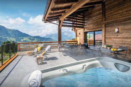 a house with a hot tub and a patio with a table and chairs at Chalet Paralpin - OVO Network in Manigod