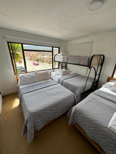 3 camas en una habitación con ventana en Hotel Rook INN, en Paipa