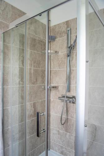a shower with a glass door in a bathroom at La Demeure du Comte in Marcillac-Vallon
