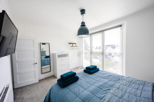 a bedroom with a bed with blue pillows and a mirror at Flat 3 Flint House Tenby - Luxury couples apartment in Tenby
