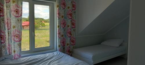 a bedroom with a window with a bed next to it at Mazurskie Wzgórze BIS z basenem in Rydzewo