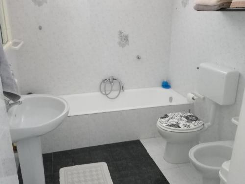 La salle de bains blanche est pourvue de toilettes et d'un lavabo. dans l'établissement Matino Casa Vacanza, à Matino