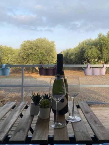 a bottle of wine sitting on a wooden table with two glasses at בקתה במטע מושב אליעד in Eli Ad