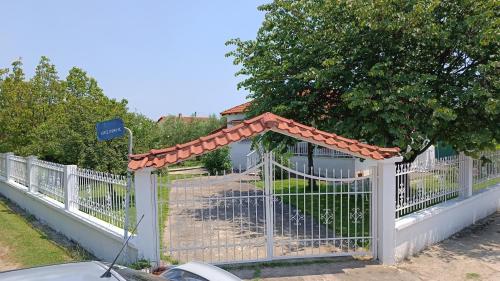 a white fence with a gate with an orange roof at Vasiliki's guest house in Vergia