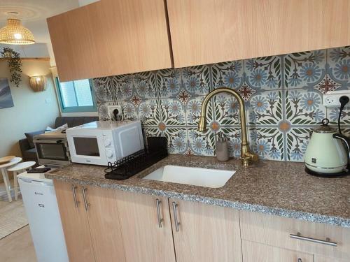 a kitchen counter with a sink and a microwave at בקתה במטע מושב אליעד in Eli Ad