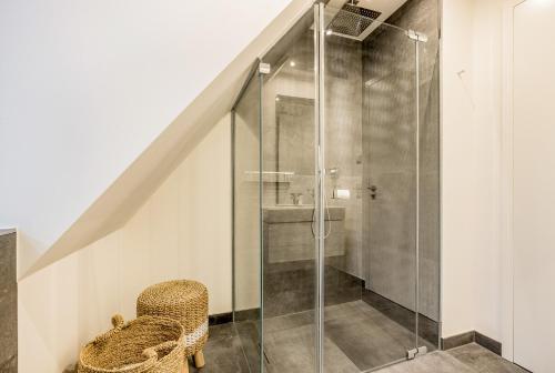 een badkamer met een glazen douche en een stoel bij Ferienhaus Witthüs - Domizil Silbermöwe - exklusiv, strand- und zentrumsnah in Westerland