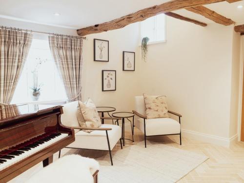 a living room with a piano and chairs at Stag Cottage in Macclesfield