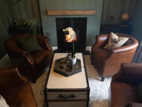 a living room with two chairs and a fireplace at Stag Cottage in Macclesfield