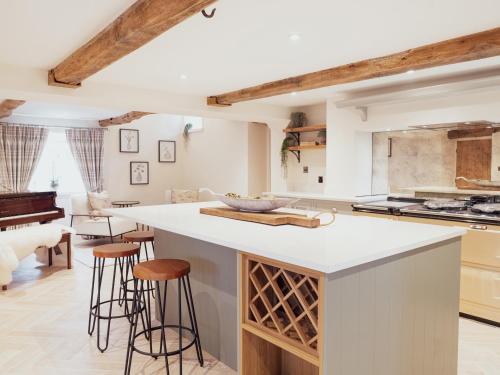 a kitchen with white countertops and bar stools at Stag Cottage in Macclesfield