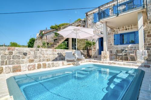 a swimming pool in front of a stone house at Villa Old Olive in Budva