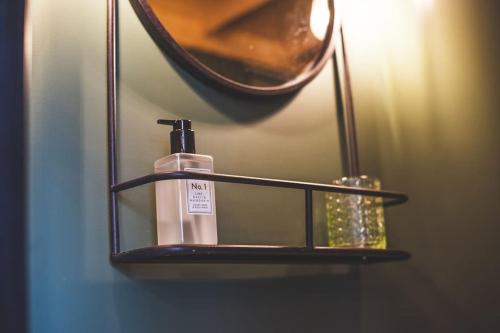 a shelf with a bottle of soap and a mirror at The Old Shop, Studio Hideout, Stoke Fleming in Stoke Fleming