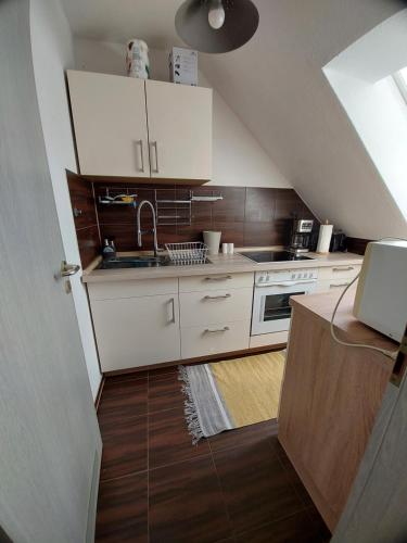 a small kitchen with white cabinets and a staircase at StayInn Möckern - 1 Zimmer Apartment für 3 Personen in Leipzig