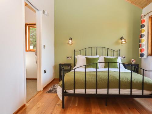 1 dormitorio con 1 cama con paredes verdes y suelo de madera en Nelli Lodge at Mile End, en Crediton