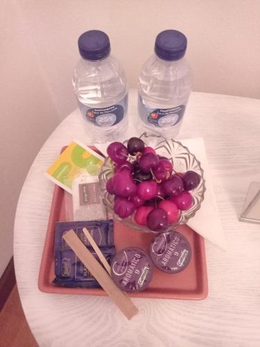a tray with a bowl of grapes and two bottles of water at Alojamento local Os Maias in Mirandela