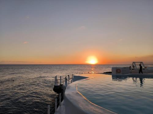 a infinity pool in the ocean at sunset at the million view room habitacion en resort solo adultos in La Laguna