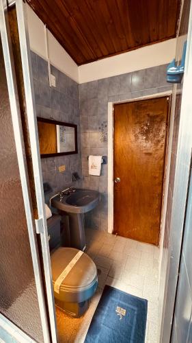 a bathroom with a toilet and a sink and a door at Hotel Rook INN in Paipa