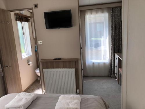 een slaapkamer met een bed en een televisie aan de muur bij Modern, stylish holiday home in Bembridge