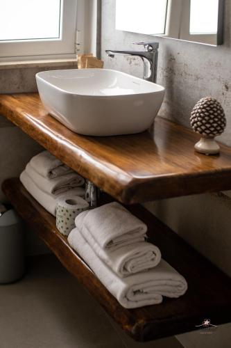 a bathroom with a sink and towels on a wooden shelf at Humboldt Luxury Rooms Taormina in Taormina