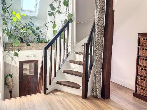 a staircase in a home with wooden railings and potted plants at Le Donjon des Rois in Dourdan