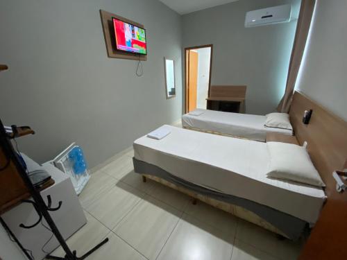 a bedroom with two beds and a tv on the wall at MAPP Hotel Aparecida-SP in Aparecida