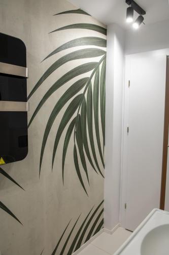 a bathroom with a mural of a palm tree on the wall at Andor apartment near park and subway in Bucharest