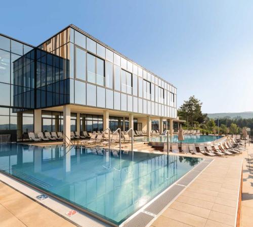 a large building with a swimming pool and chairs at Fruške Residences in Vrdnik