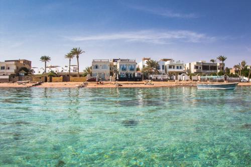 a beach with houses and a boat in the water at Skyrock Dahab in Dahab