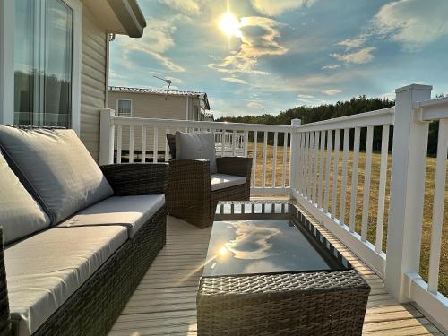 a patio with a couch and a table on a deck at Highland Holiday Getaways in Embo