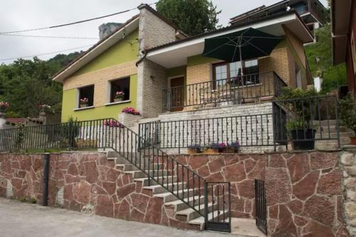 una casa amarilla con escaleras y sombrilla en Casa La Bolera, en Carreña