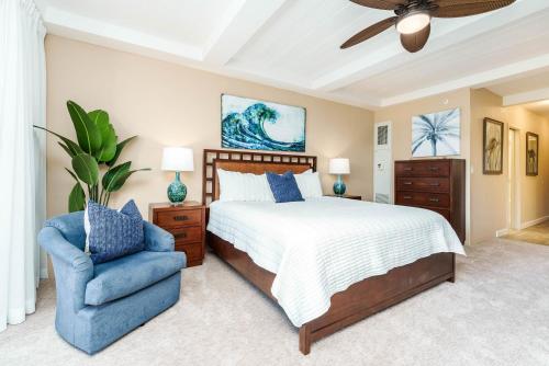 um quarto com uma cama e uma cadeira azul em Whaler 518 OceanView Studio Condo condo em Lahaina