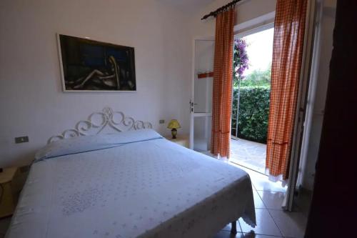 um quarto com uma cama branca e uma grande janela em Bilocale a due passi dalla spiaggia em Marina di Campo