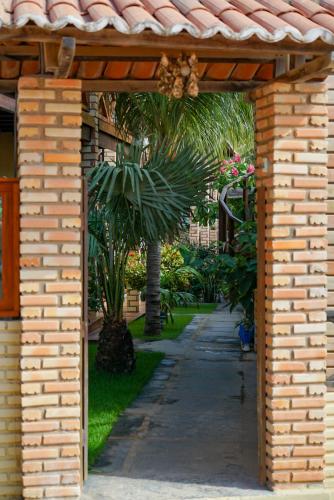 a brick archway with a palm tree in a yard at Casa do velejador in Barra Grande