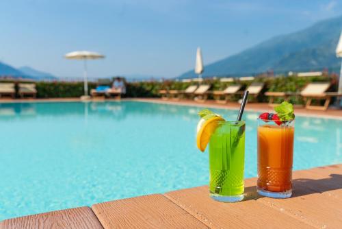 Dois cocktails sentados numa mesa ao lado de uma piscina em Hotel Regina em Gravedona