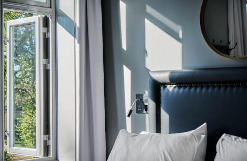 a bedroom with a blue wall and a mirror and a bed at Hotel Filip in Oslo